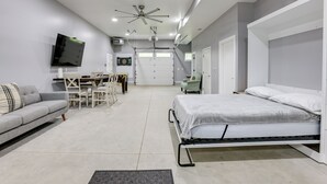 Ein modernes Schlafzimmer mit Bett, Sofa, Fernseher und Deckenventilator.
