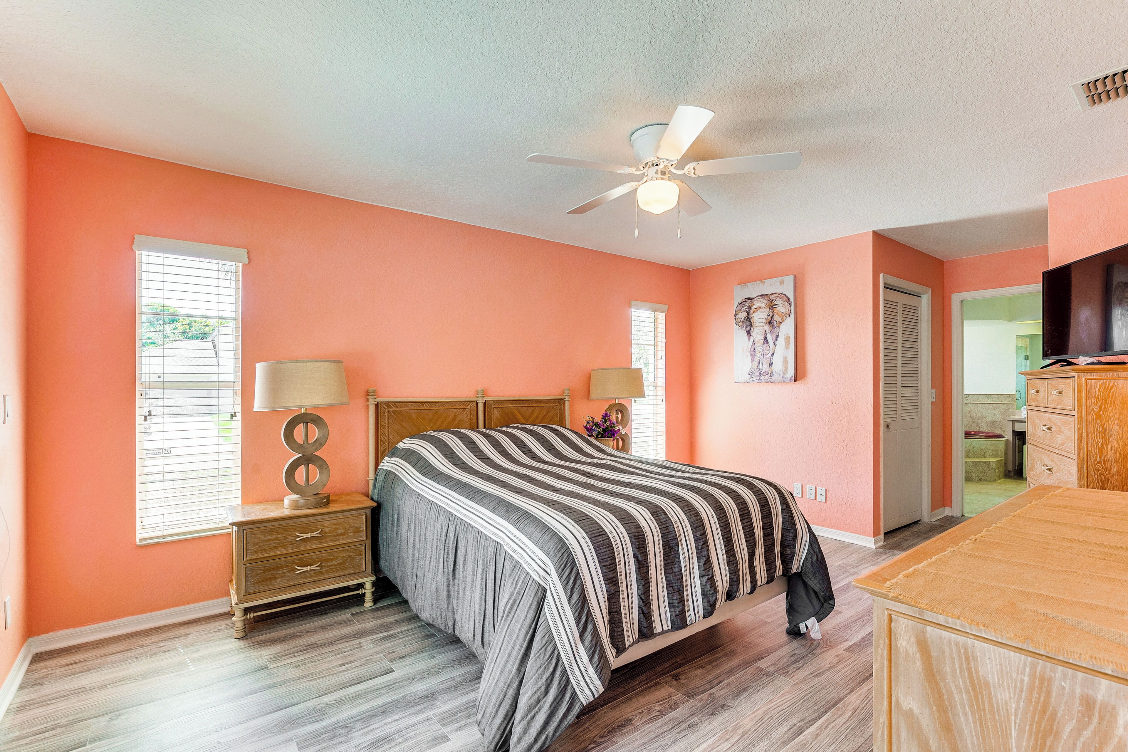 A bedroom with a bed, nightstands, a ceiling fan, and a dresser.