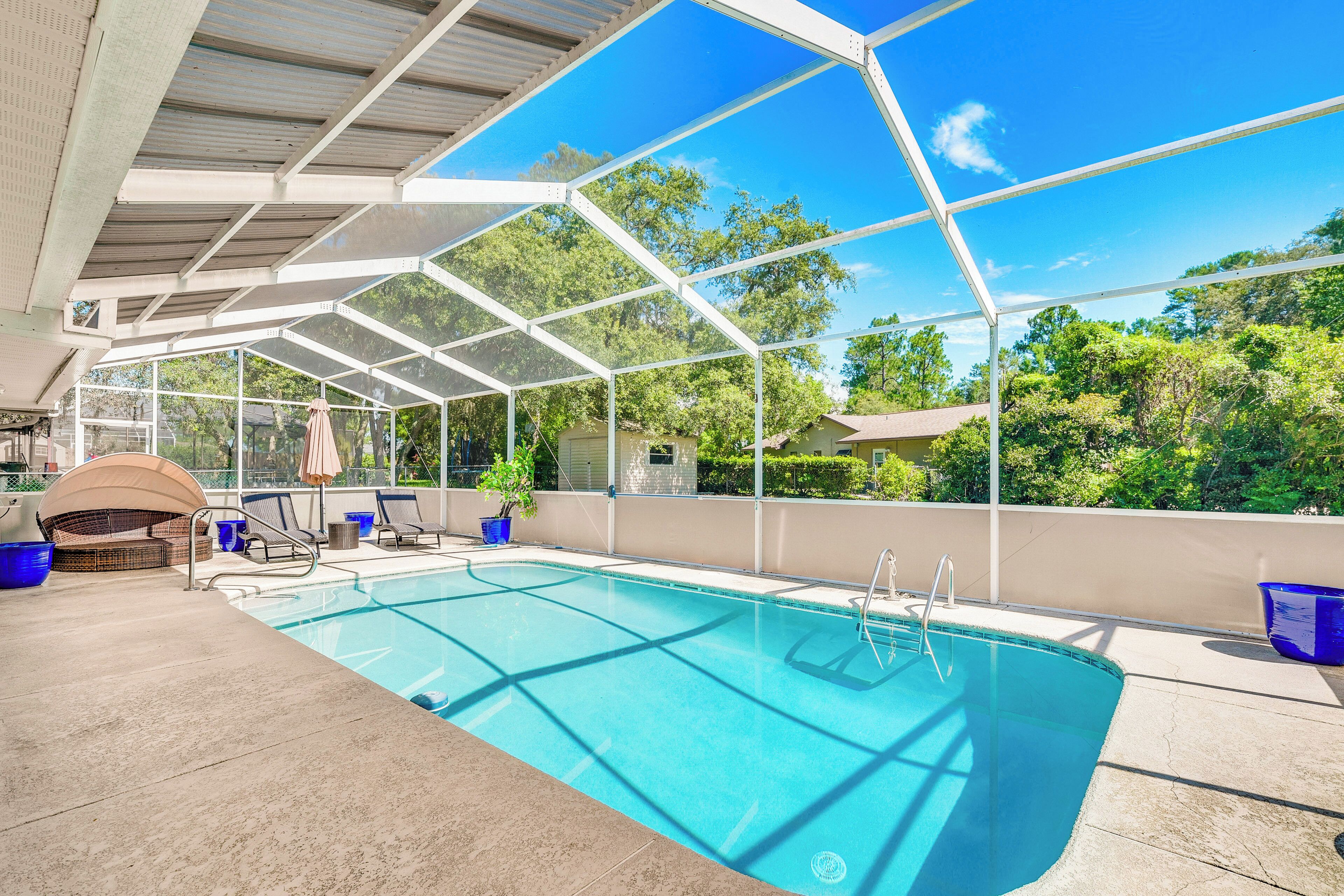 An indoor swimming pool with a glass ceiling, lounge chairs, and a barbecue area.