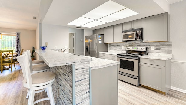 A modern kitchen with a central island, stainless steel appliances, and a tiled backsplash. - Spring Hill Home: Heated Pool, 9 Mi to Beach! (Spring Hill)
