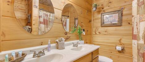 A wooden cabin bathroom with two sinks, a toilet, and a mirror.