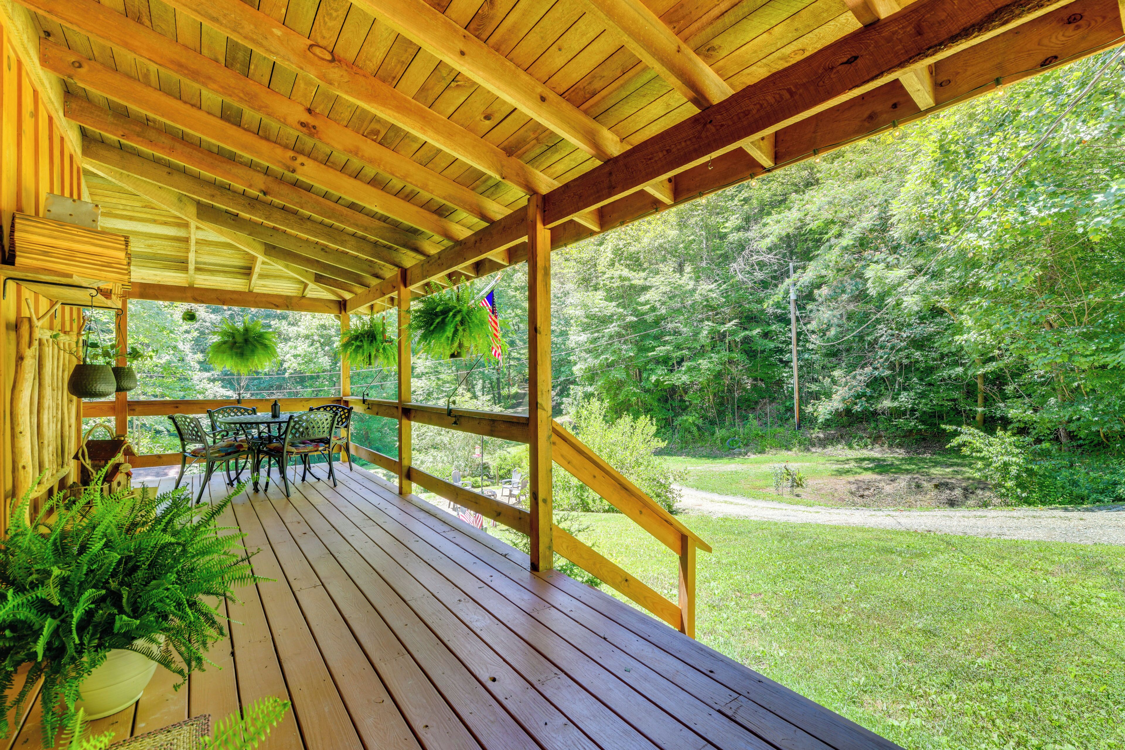 A wooden deck with outdoor furniture, a railing, and a view of a forested area.