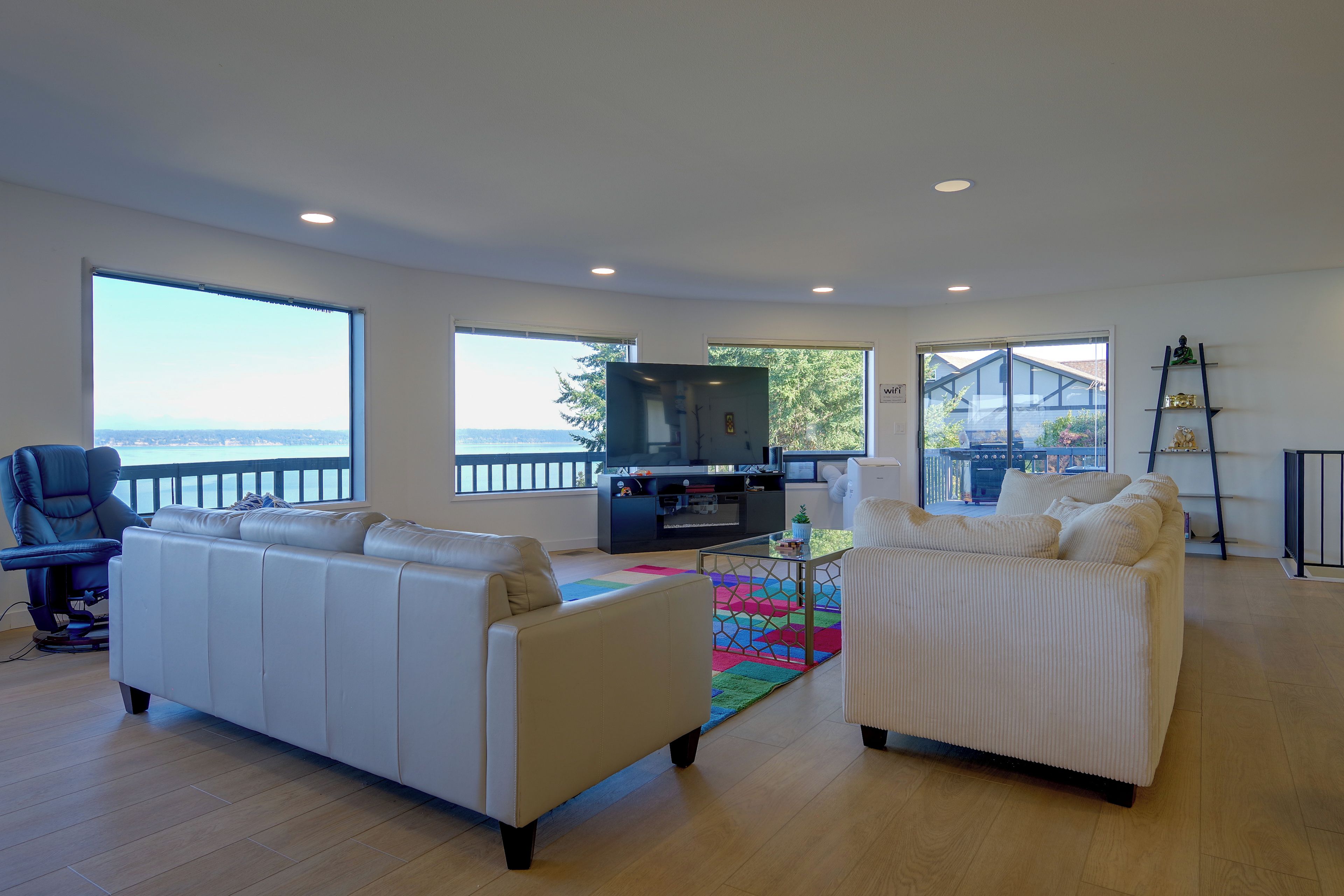 A spacious living room with a large window, a television, and a balcony.