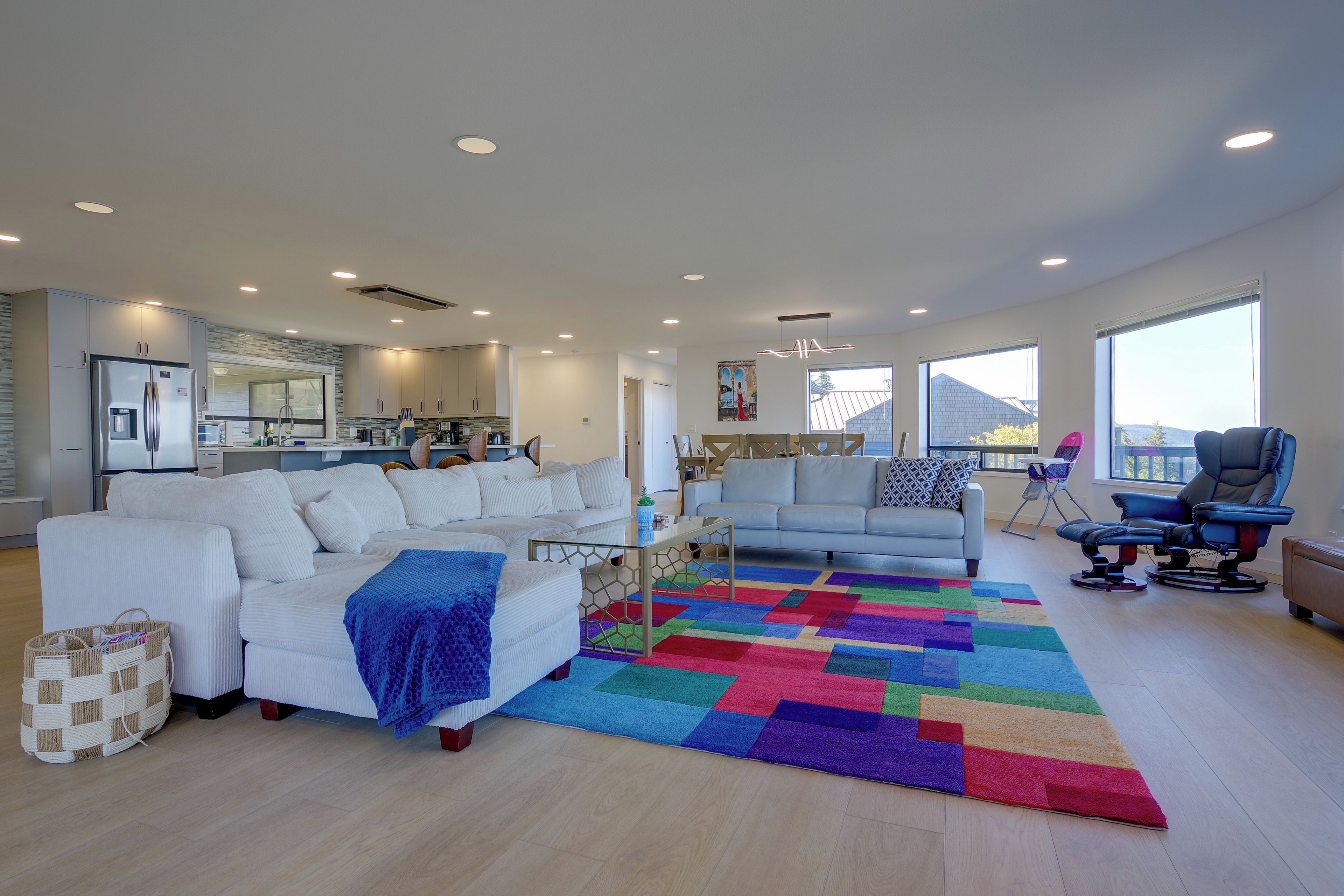 A spacious living room with a large sectional sofa, a coffee table, and a colorful rug.