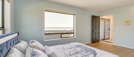 Une chambre à coucher avec un grand lit, une fenêtre donnant sur un beau paysage et une porte menant à une autre pièce.