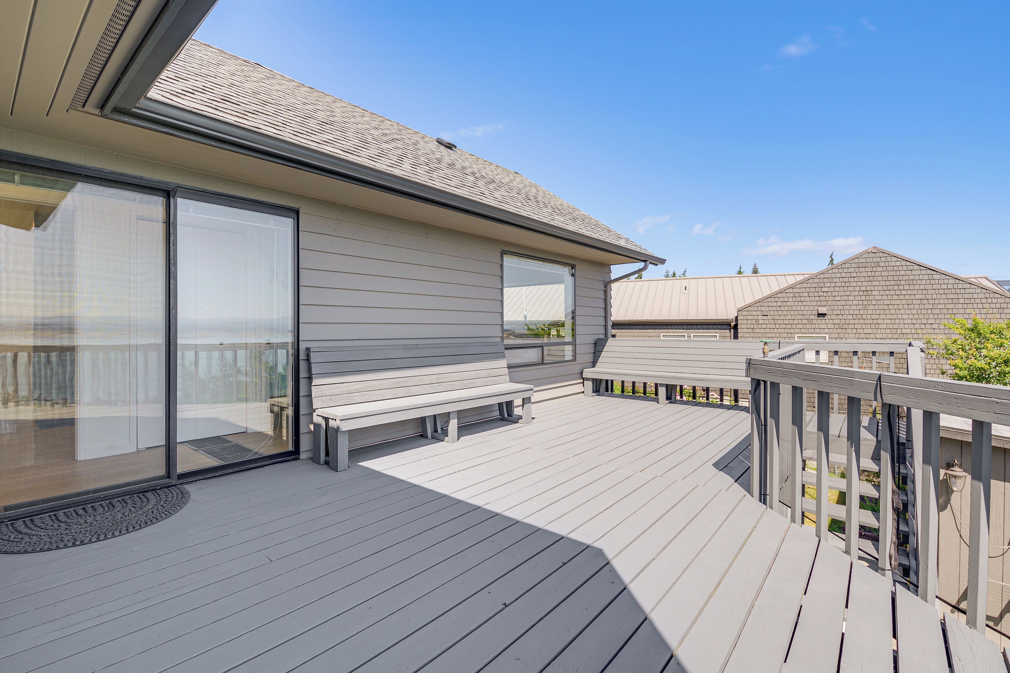 Una casa moderna con una terrazza, ampie porte scorrevoli in vetro e un patio coperto.