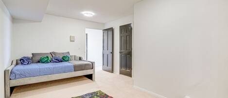 A bedroom with a bed, a carpet with gaming graphics, and two doors.