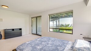 Een slaapkamer met een bed, een dressoir en een schuifdeur die leidt naar een balkon.