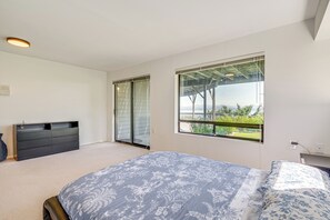 Une chambre à coucher comprenant un lit, une commode et une porte-fenêtre coulissante donnant sur un balcon.