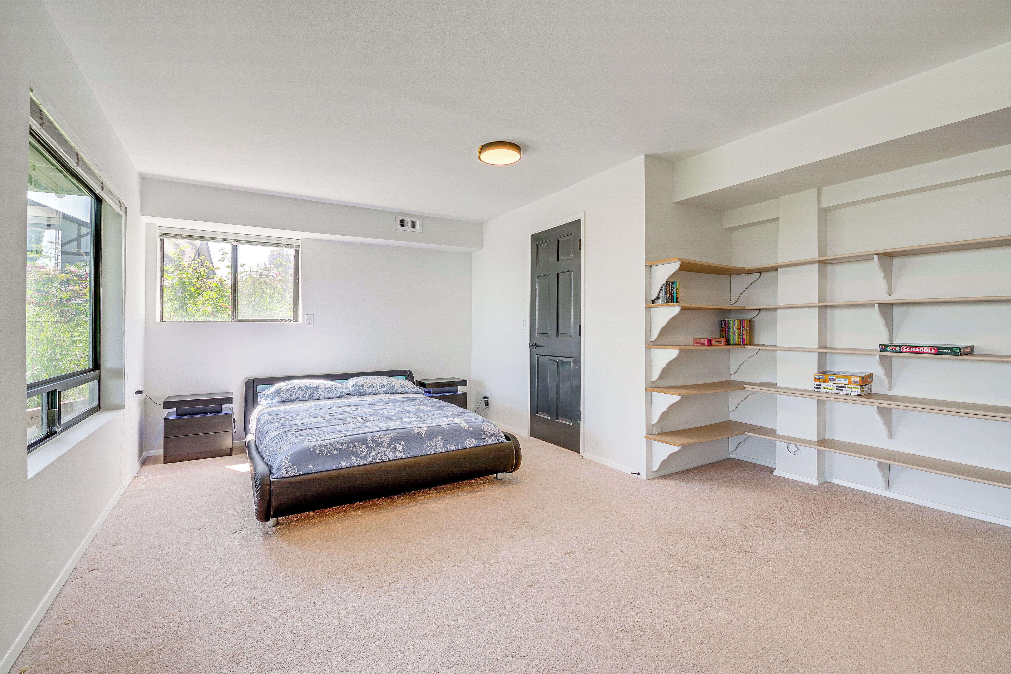 A bedroom with a bed, a nightstand, a bookshelf, and a door.