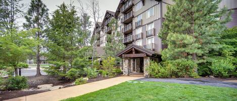 A multi-story building with a stone facade, a covered entrance, and a well-maintained lawn.