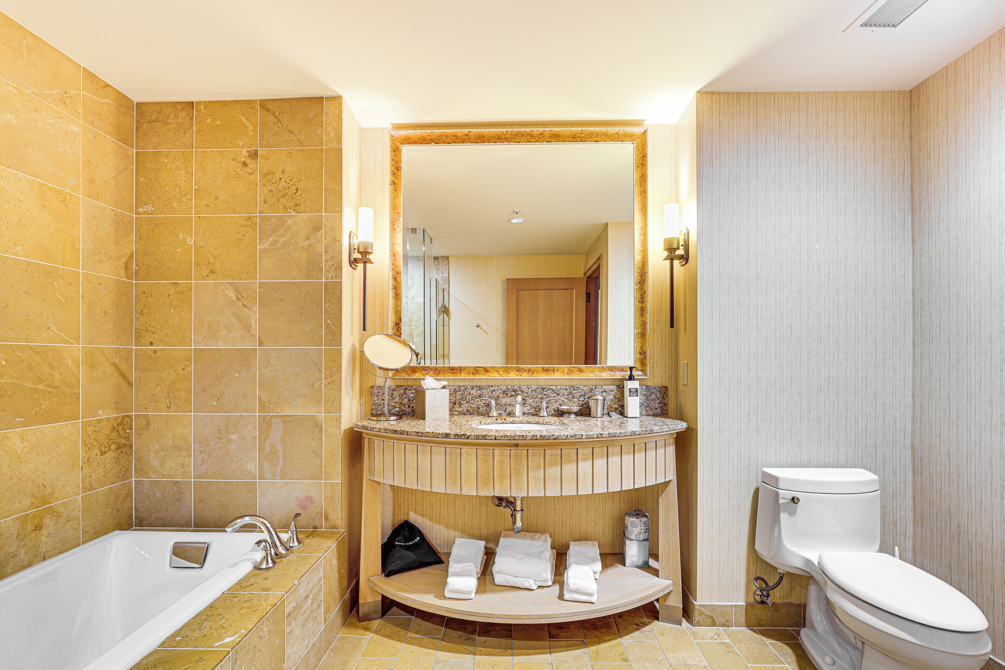 A bathroom with a bathtub, a sink with a mirror, and a toilet.