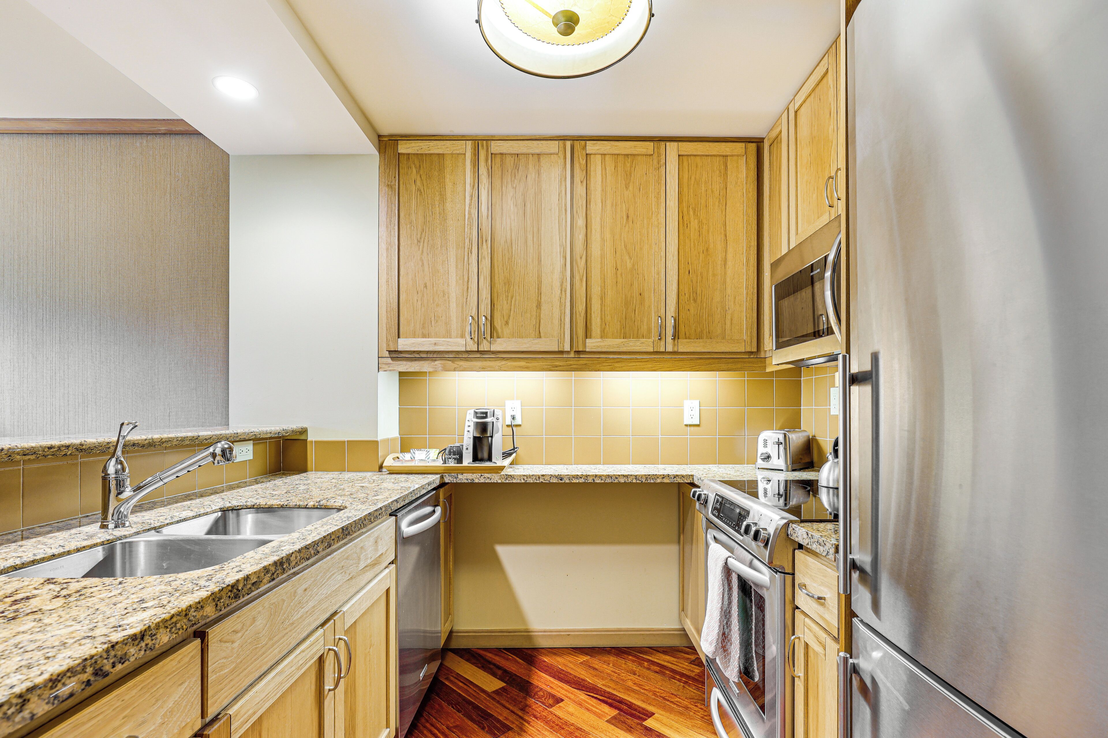 A kitchen with wooden cabinets, stainless steel appliances, a granite countertop, and a dishwasher.