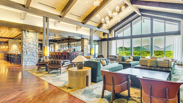 Eine geräumige Lobby mit Holzboden, Steindetails und großen Fenstern mit Blick auf Grünflächen.