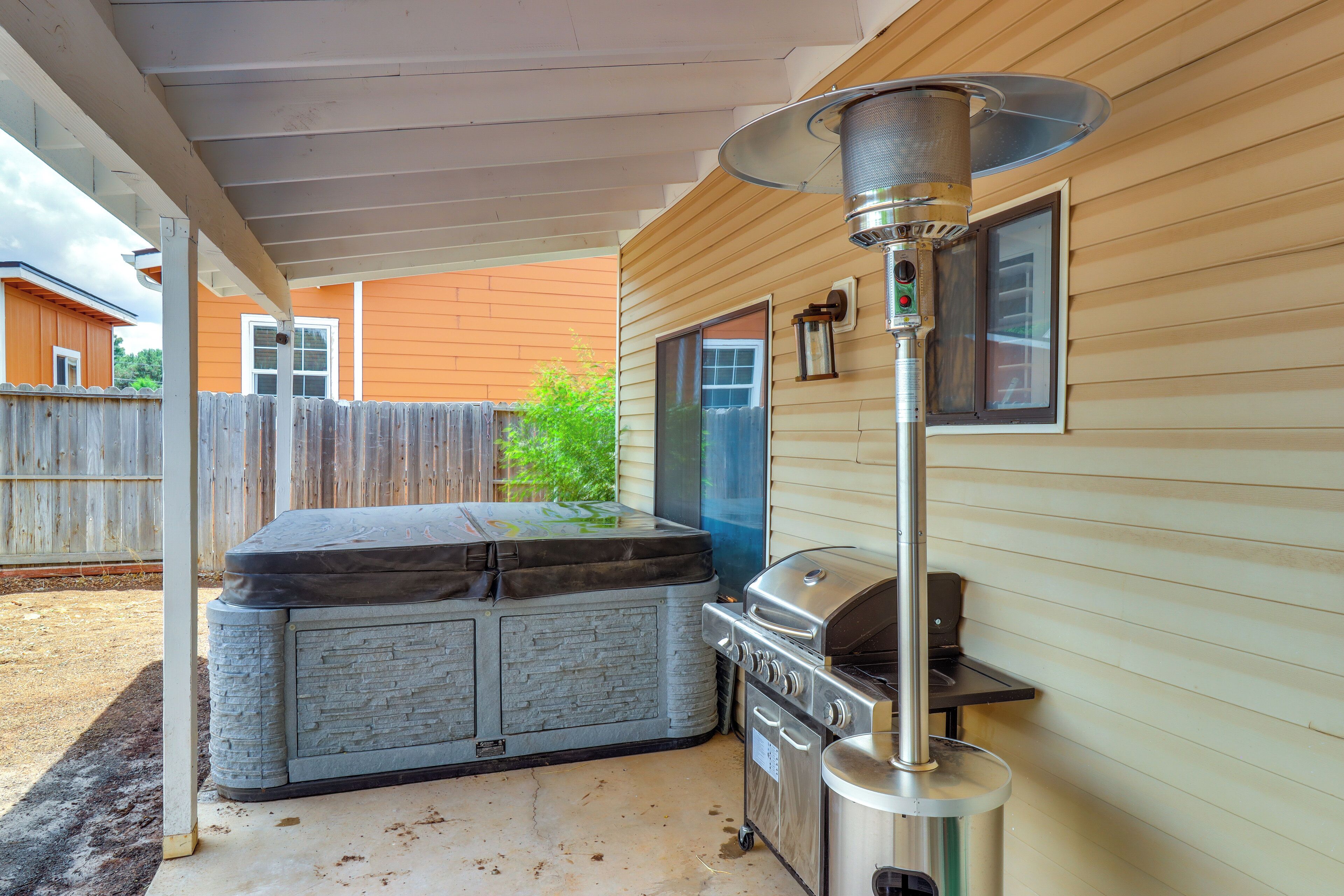 A covered outdoor area with a barbecue grill, a hot tub, and a patio table.