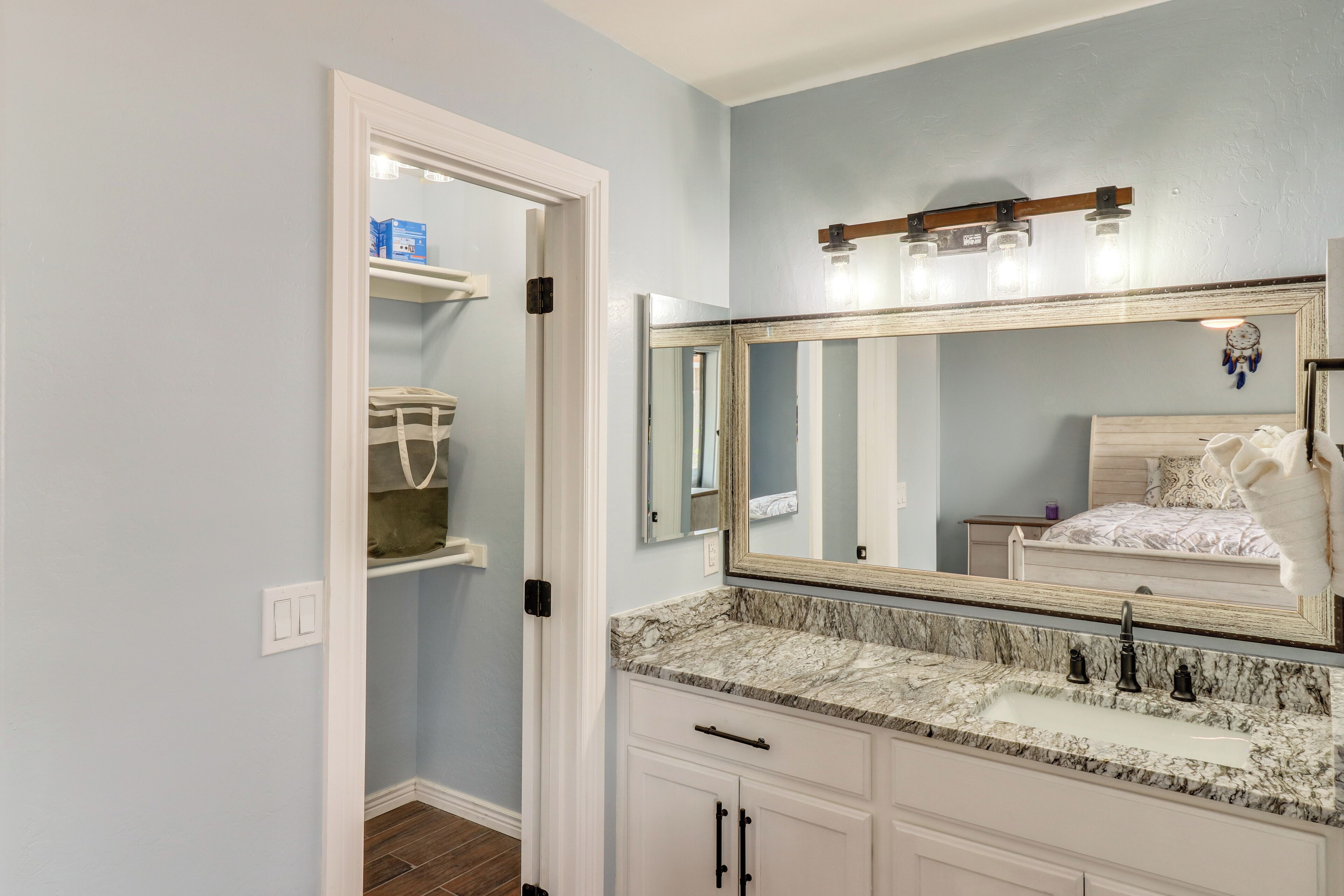 Un baño con un espejo grande, una encimera de mármol y un mueble blanco.
