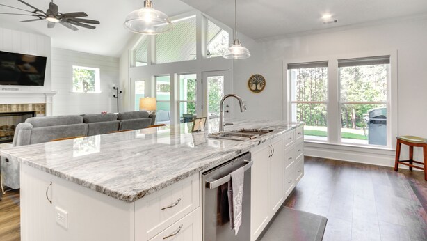 A spacious kitchen with a large island, white cabinetry, and a dining area with a gray sofa. - Lakefront Mccormick Retreat w/ Patio & Views (McCormick)
