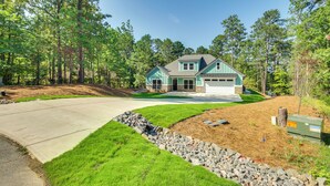 A two-story house with a garage, surrounded by a well-maintained lawn and a wooded area. - Lakefront Mccormick Retreat w/ Patio & Views (McCormick)
