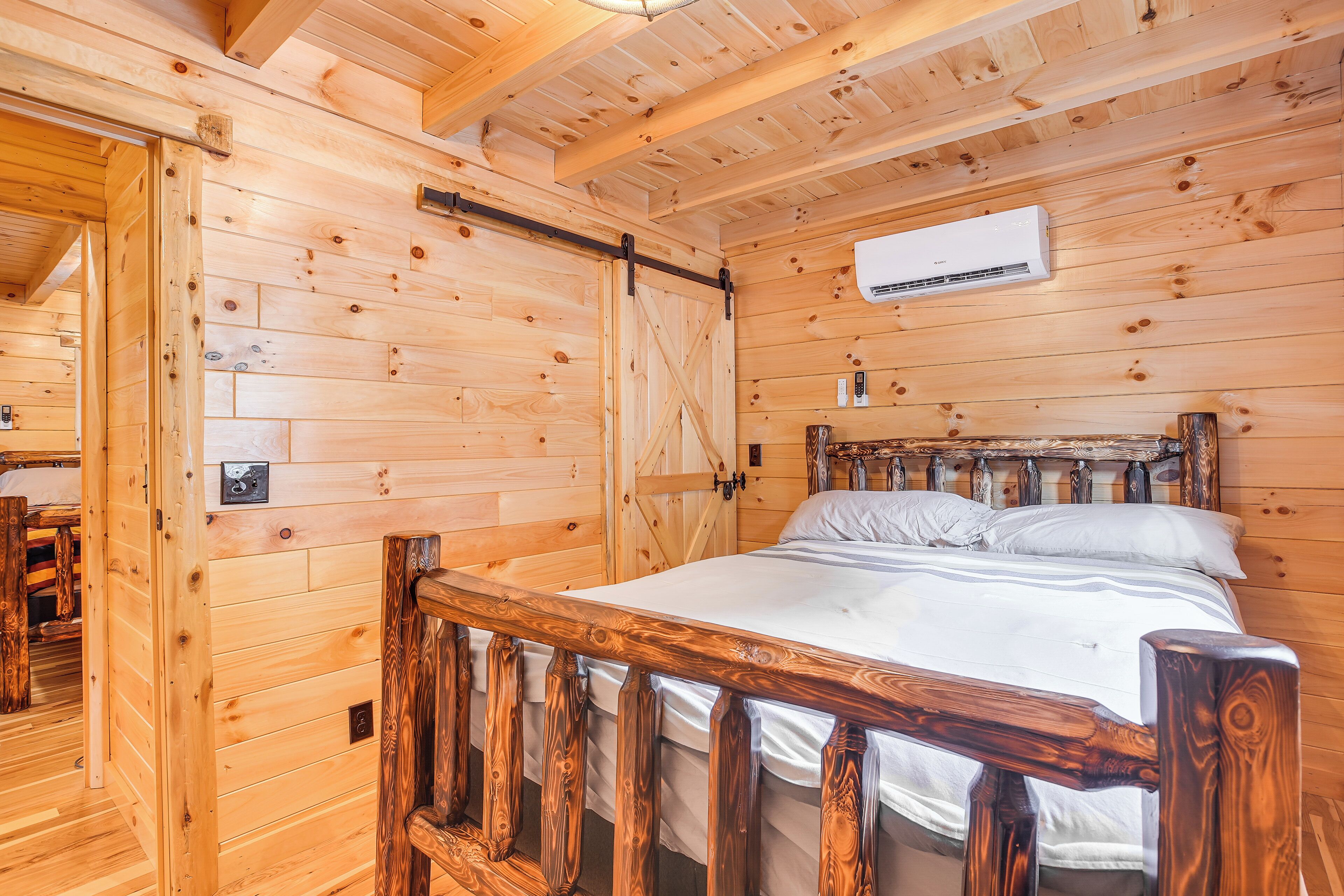 Ein Schlafzimmer in einer Holzhütte mit Bett, Holzwänden und einer Schiebetür.