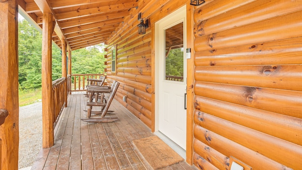 Une cabane en bois avec une véranda, une porte et une fenêtre.