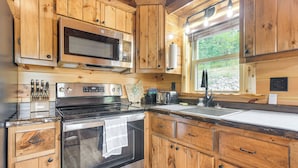 Une cuisine dotée de meubles en bois, d’appareils électroménagers en acier inoxydable et d’une fenêtre offrant une vue sur l’extérieur.