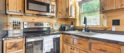 Une cuisine dotée de meubles en bois, d’appareils électroménagers en acier inoxydable et d’une fenêtre offrant une vue sur l’extérieur.