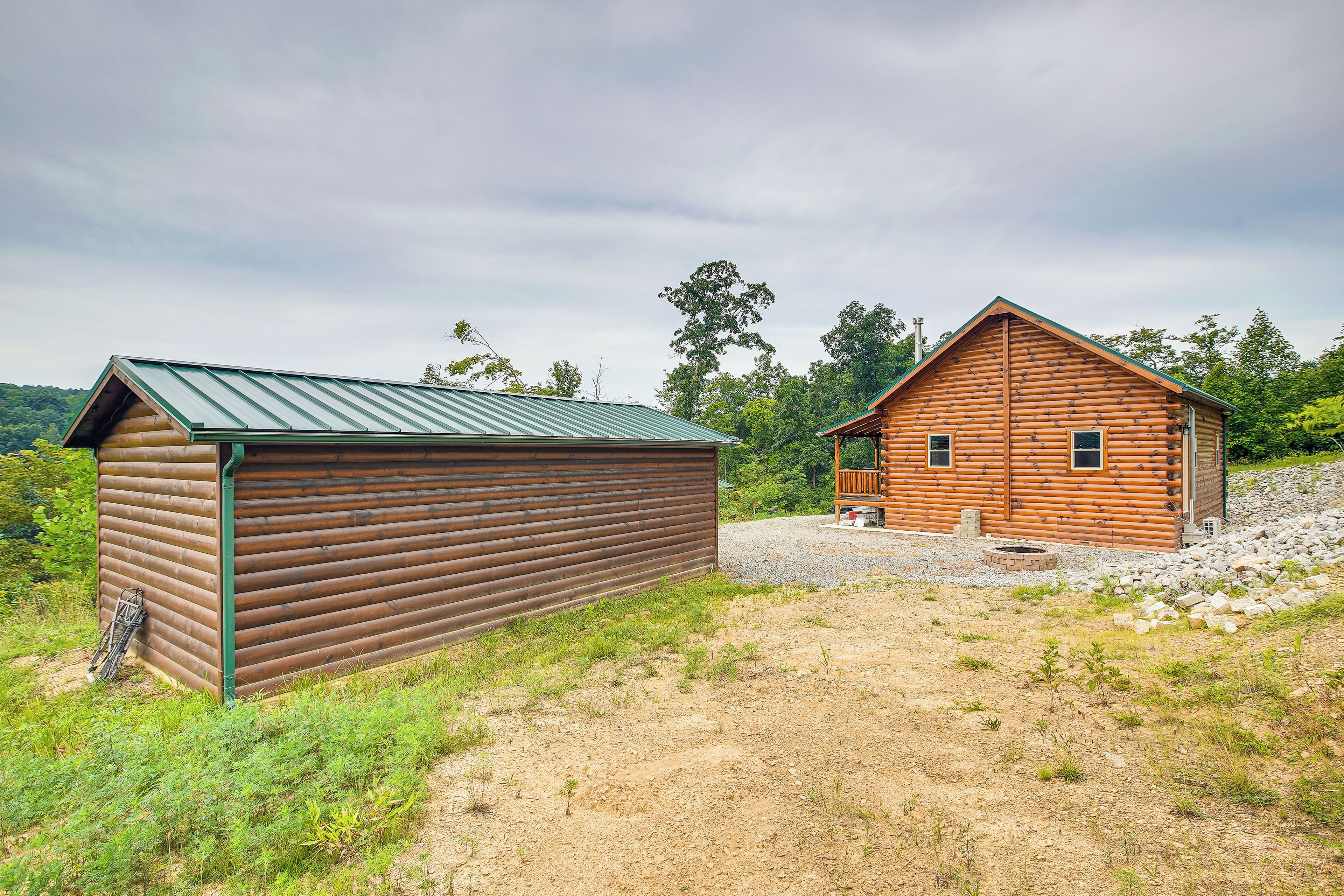 Une cabane rustique avec un toit en métal et un revêtement extérieur en bois, entourée d’un chemin de gravier et de verdure.
