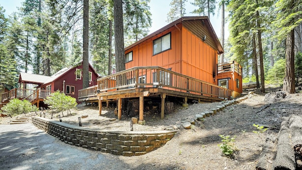 A cabin with a wooden deck and a stone retaining wall.