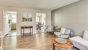 A spacious living area with a wooden floor, a white sofa, a round coffee table, and a dining area in the background. - 5 Mi to Downtown Harrisburg - Family Home! (Harrisburg)