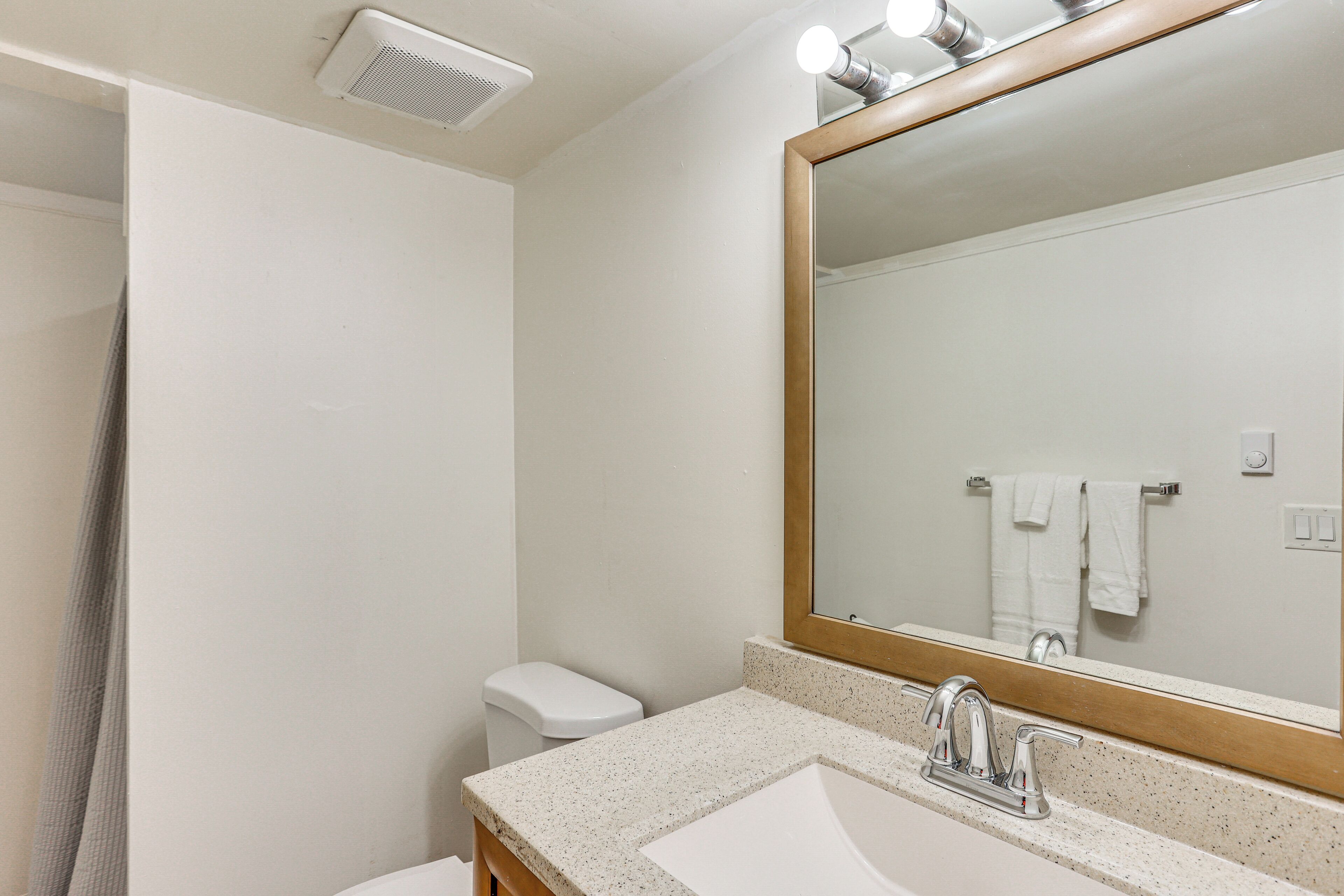 A bathroom with a white sink, a large mirror, and a shower curtain.