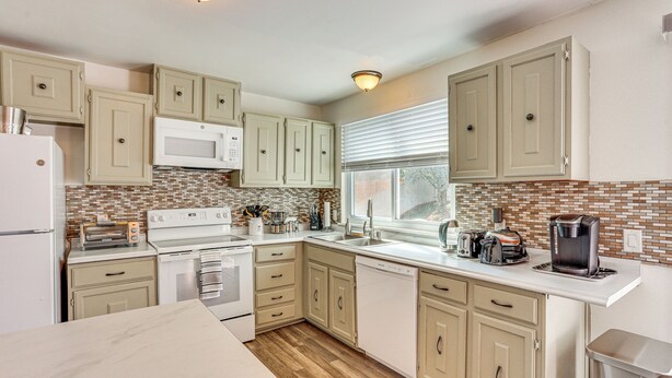 A kitchen with beige cabinets, a white countertop, a microwave, a toaster, a sink, and a window with blinds. - 5 Mi to Downtown Harrisburg - Family Home! (Harrisburg)