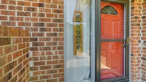 A red door with a glass panel and a metal handle, set in a brick wall. - Waterfront Nags Head Townhome w/ Amenity Access! (Nags Head)