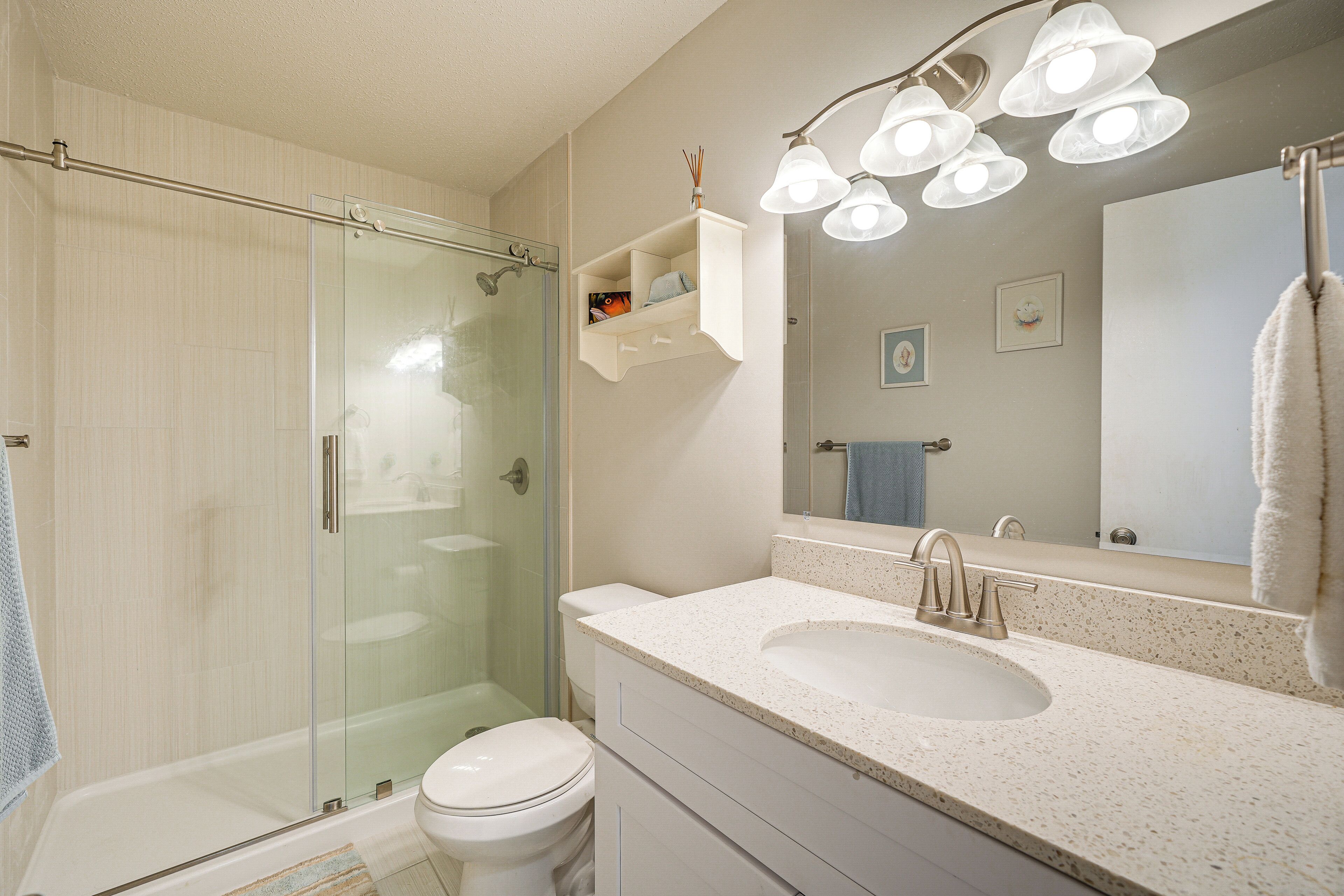 Une salle de bain avec une douche à parois de verre, un lavabo blanc et un meuble-lavabo avec des tiroirs.
