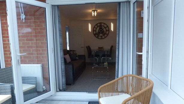 Een moderne woonkamer met een glazen deur die leidt naar een eethoek.