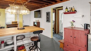A kitchen with wooden beams, a hanging light fixture, a wooden bar counter, and a red cabinet with bottles on top. - The Pink House: Central Location | Pet-Friendly (Kill Devil Hills)
