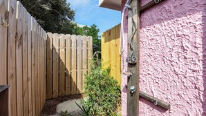 A wooden fence, a pink wall, and a small garden area with plants. - The Pink House: Central Location | Pet-Friendly (Kill Devil Hills)
