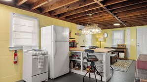 A compact kitchen with a white stove, refrigerator, and wooden ceiling beams. - The Pink House: Central Location | Pet-Friendly (Kill Devil Hills)