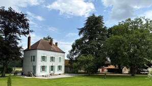 A two-story white building with green shutters, a grassy yard, and surrounding trees. - Historic 1830 Mansion with Spa, Games, Pets Allowed (Jaligny-sur-Besbre)