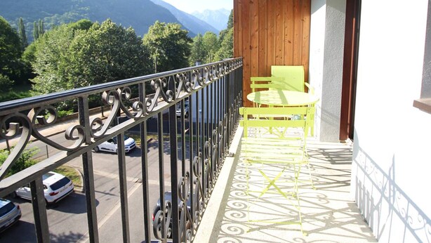 A balcony with a view of mountains, a wooden wall, and a yellow chair.