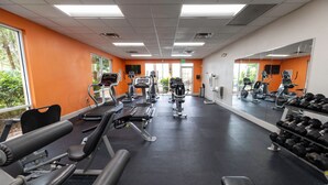 Un gimnasio con cintas de correr, máquinas de pesas y mancuernas.
