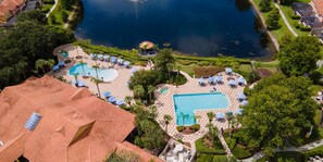 Eine Luftaufnahme eines Resorts mit mehreren Schwimmbecken, Liegestühlen und Palmen.