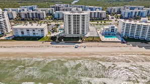 A coastal residential area with multiple high-rise buildings, a beach, and a swimming pool.
