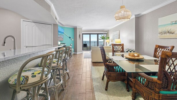 A spacious kitchen with a large island, wooden chairs, and a dining table with a chandelier.