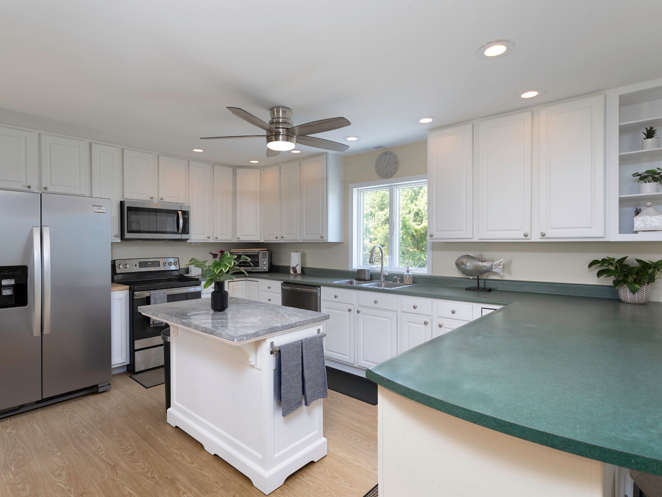 A modern kitchen with white cabinetry, a stainless steel refrigerator, a microwave, and a built-in oven.