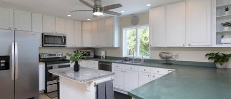A modern kitchen with white cabinetry, a stainless steel refrigerator, a microwave, and a built-in oven.
