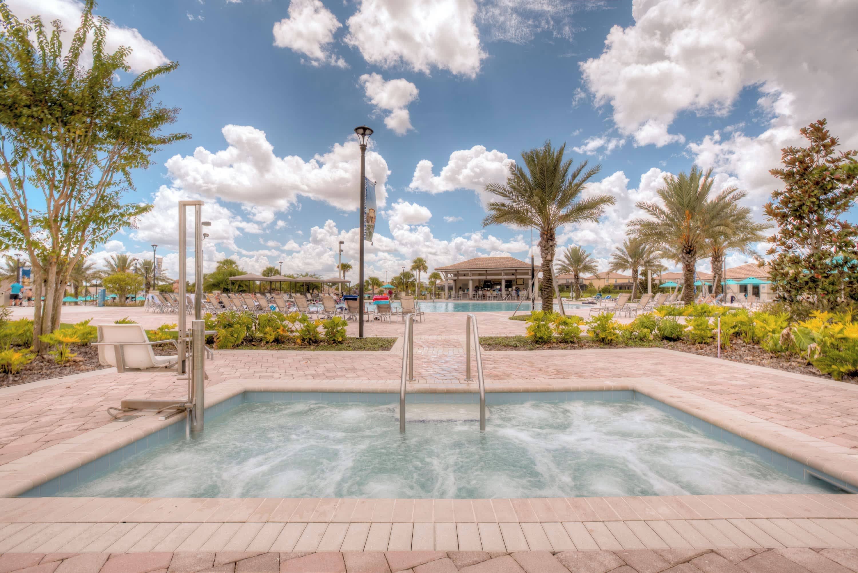 A pool area with a hot tub, surrounded by palm trees and lounge chairs.
