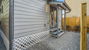 A house with a white exterior, a wooden fence, and a gravel driveway. - HTX Ultra Hotel Suite #2 (Houston)