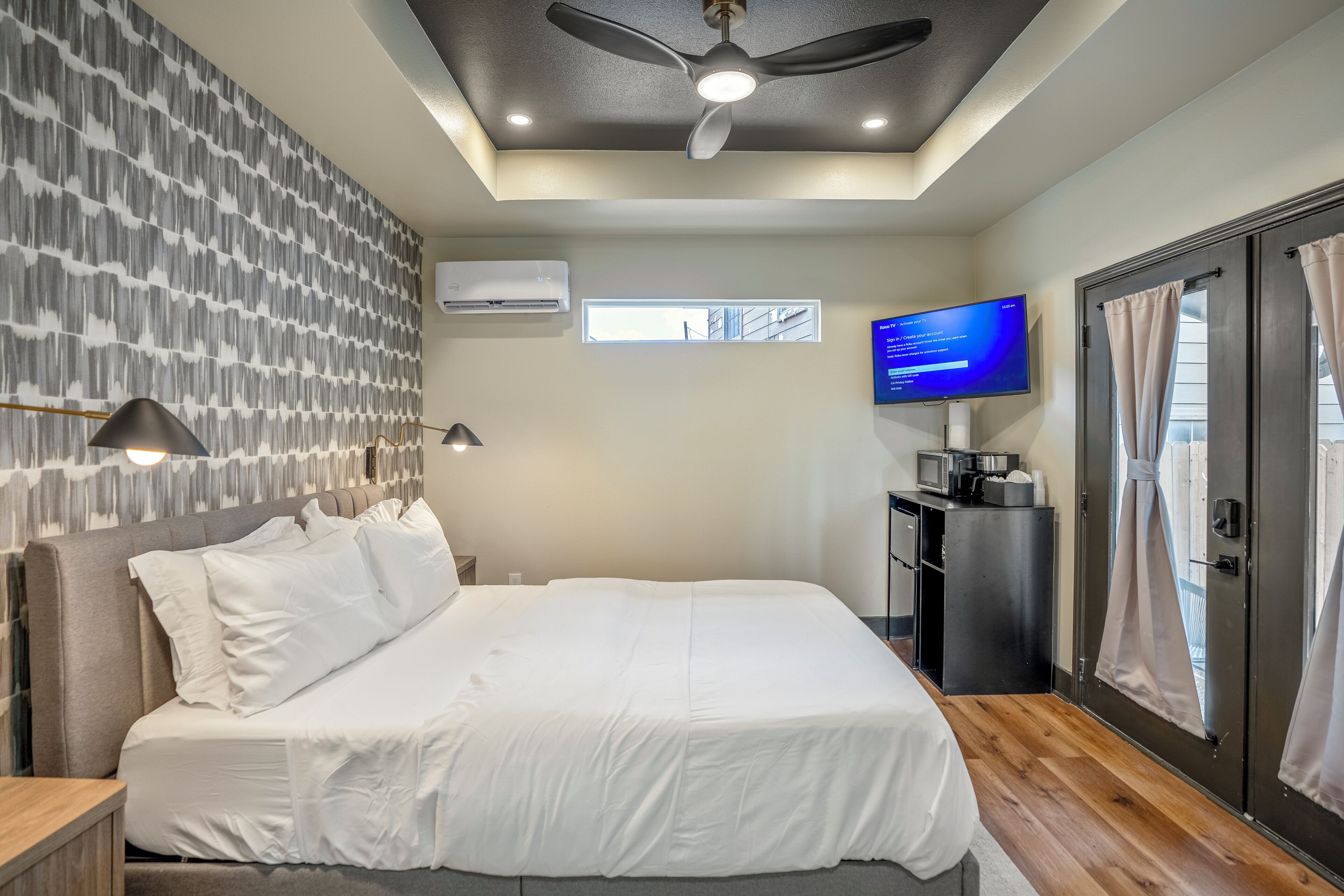 Une chambre d’hôtel moderne dotée d’un grand lit, d’un ventilateur de plafond, de la climatisation, d’un téléviseur à écran plat et offrant une vue par la fenêtre.