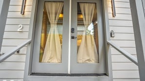 A double door with a number '2' on the wall, a doorbell, and a small window with curtains. - HTX Ultra Hotel Suite #2 (Houston)
