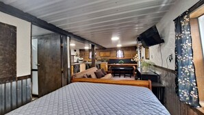 Una habitación pequeña con cama, mesa de comedor y zona de cocina.